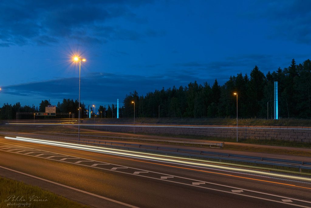 Moottoritien pinta pimeällä. Tien reunassa valopylväs.