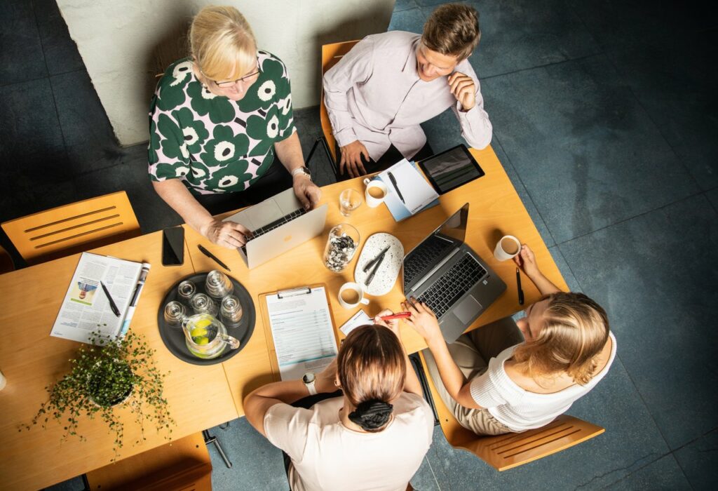 Autamme yrityksiä verkostojen luomisessa. Kuvassa neljä henkilöä kahvipöydän äärellä ylhäältä kuvattuna.