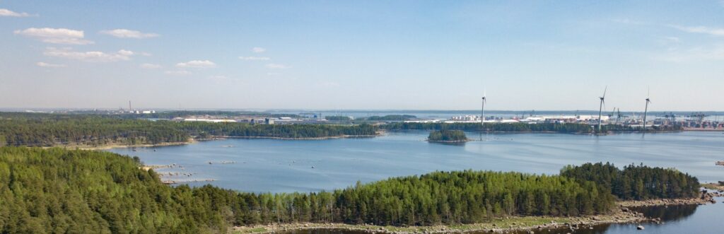 Energiateollisuudelle on tilaa Kotkan-Haminan seudulla. Ilmakuva Santalahden ja Mussalon alueelta, merimaisema ja tuulimyllyjä.
